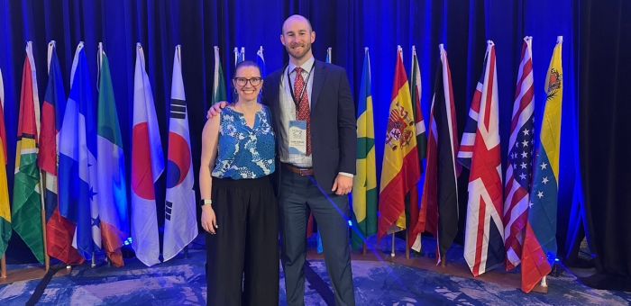 Knauss Fellows Hayley Lemoine (left) and Clark Morgan (right) at conference standing in front of world country flags