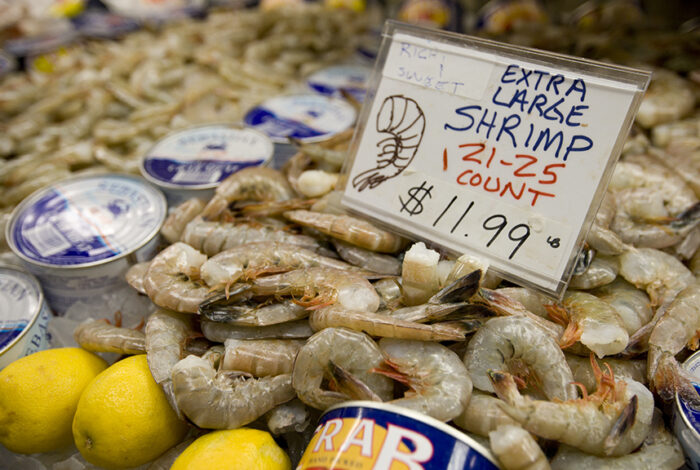 Shrimp and cans of crab meat on display for sale at a seafood store.
