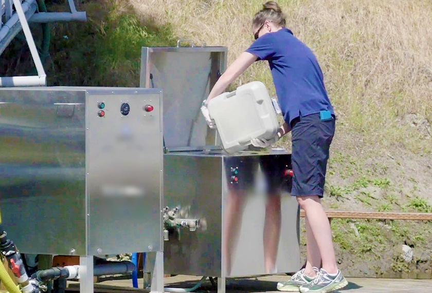 outreach educator demonstrates how to empty a portable toilet into a dump station for boaters