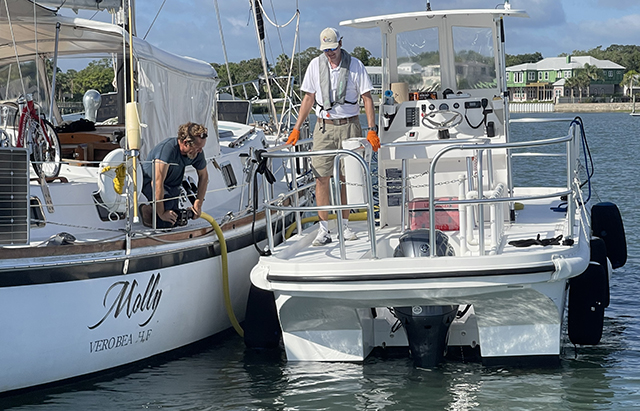 mobile pumpout station in use; marina attendant helps boater pumpout boat in channel