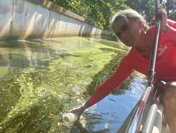 woman on boat collecting water sample