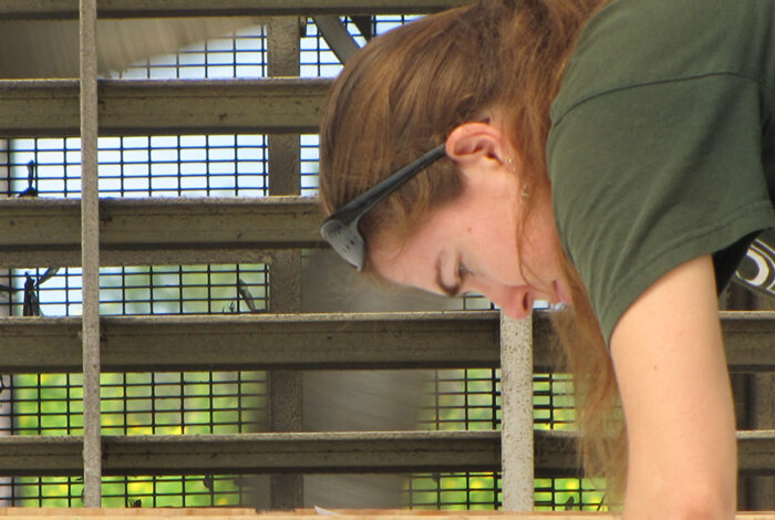 Woman leaned over beside of building exhaust fan