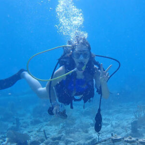 student diver underwater giving a peace sign to the camera