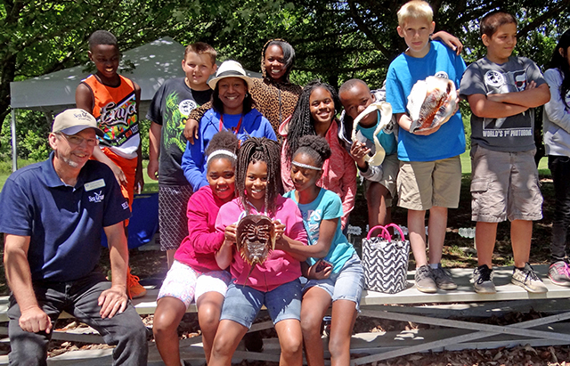 educators poses with young class of students holding up horseshoe crab 