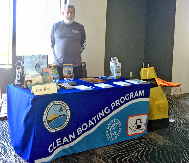 clean boating coordinator smiling from next to a table displaying clean boating program outreach materials