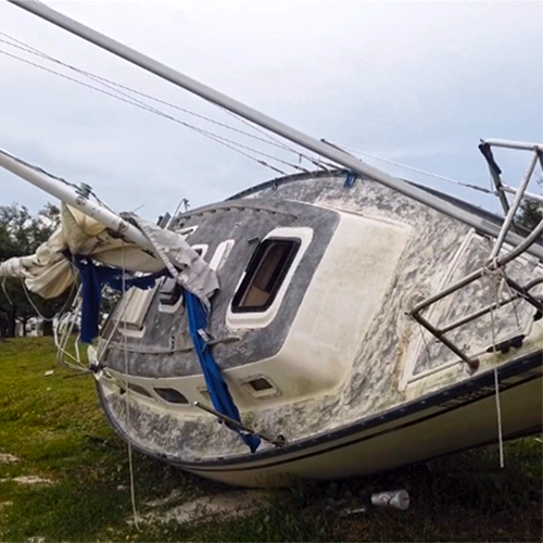 Large white sailboat with a faded blue deck rests high and dry as a result of Hurricane Michael.