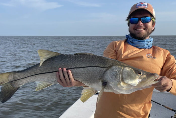 student researcher holding fish as part of his research on the diets of herbivorous fishes