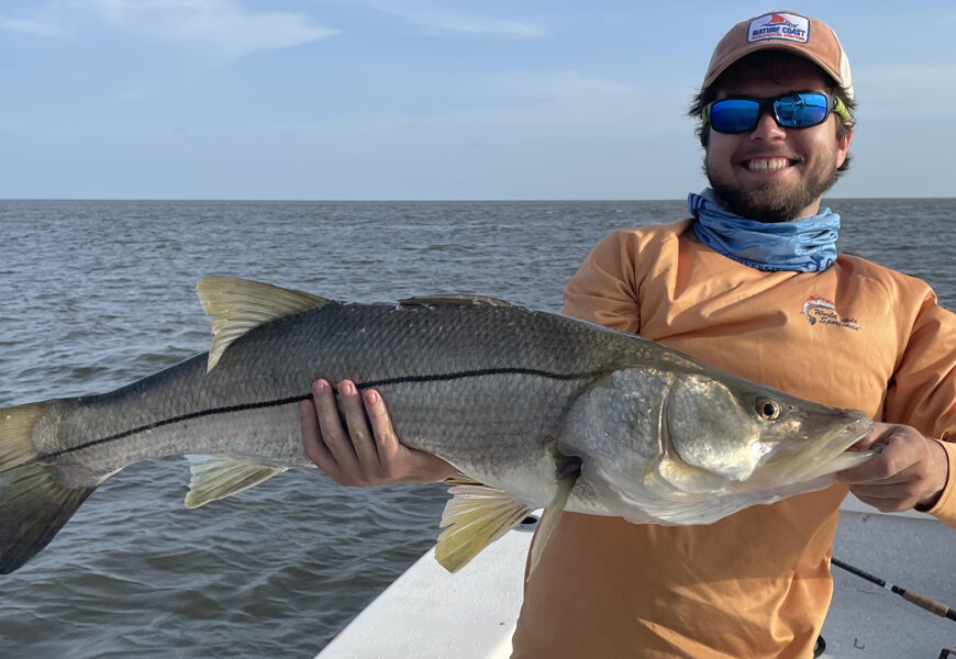 student researcher holding fish as part of his research on the diets of herbivorous fishes