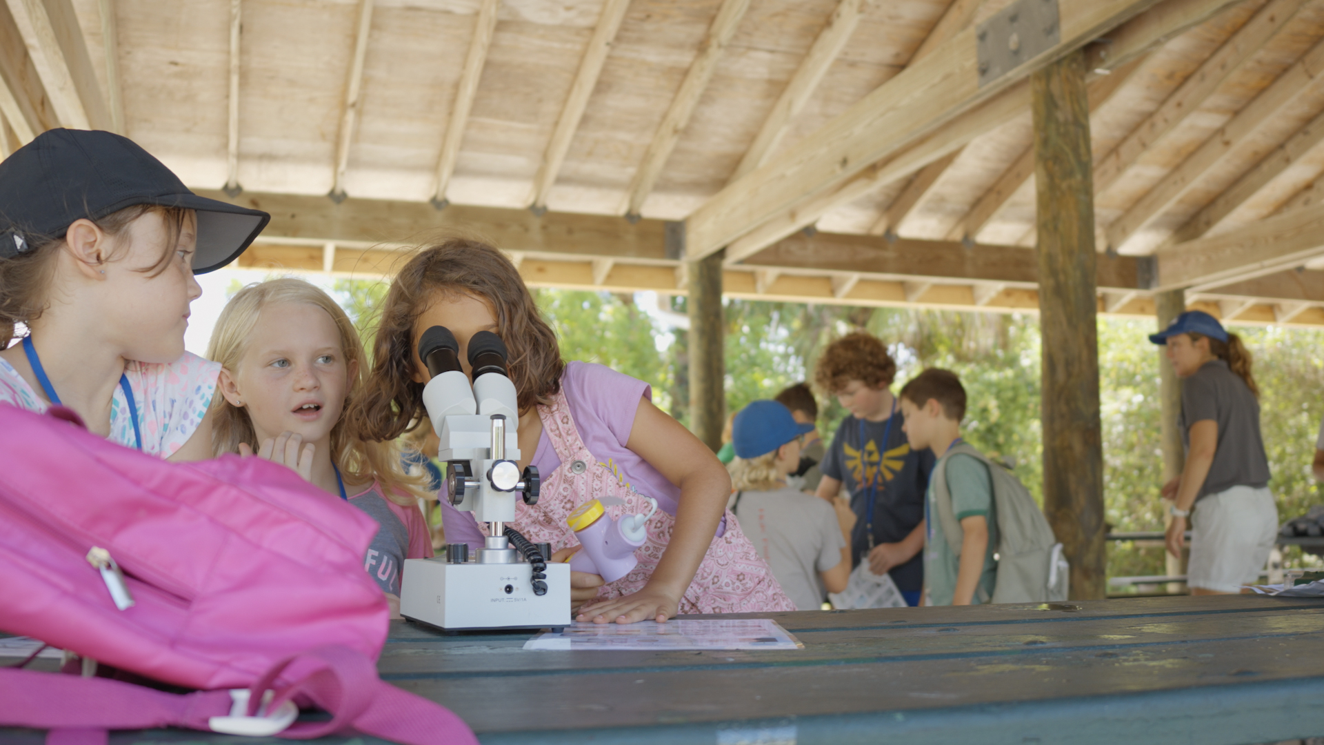 kids looking in microscope Carolyn Kovacs in background