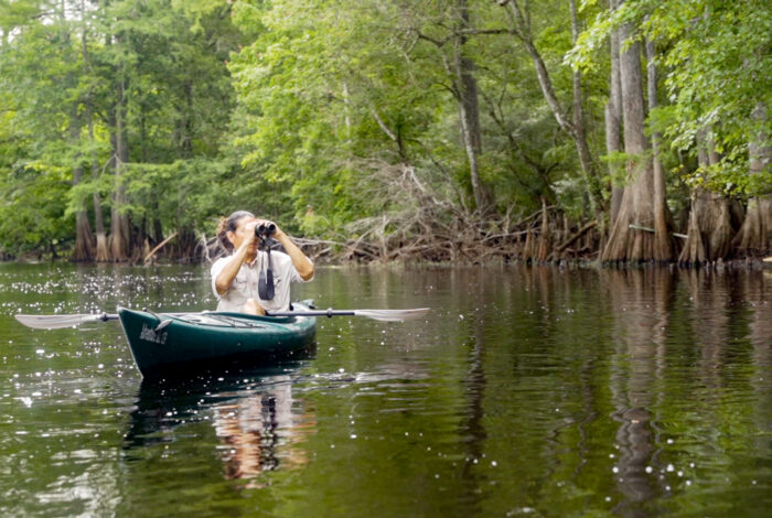 Armando Ubeda in kayak holding binoculars