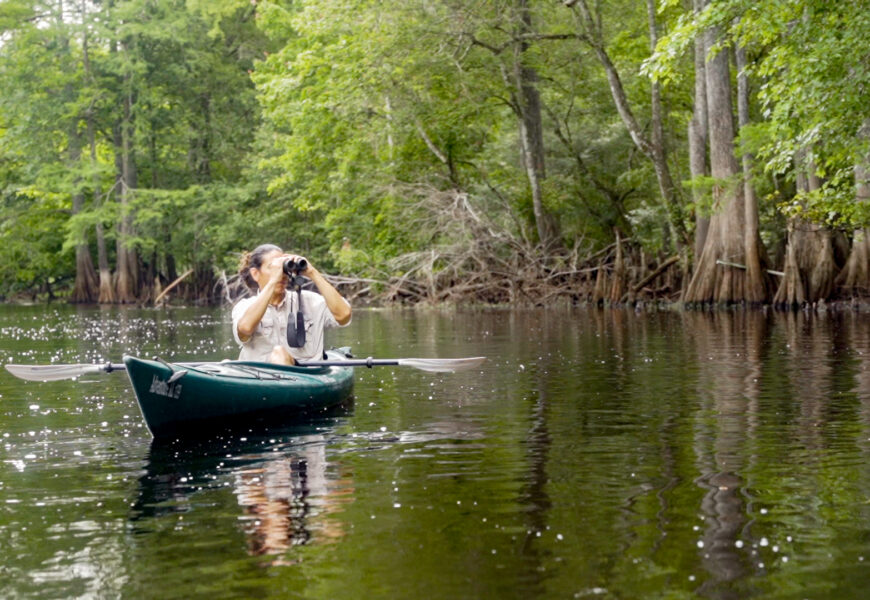 Armando Ubeda in kayak holding binoculars