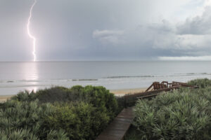 lightning strike in the ocean in background dunes and boardwalk in foreground