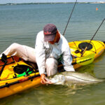 man on kayak holding fish