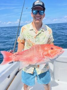 Roberto holding a red snapper on a boat.