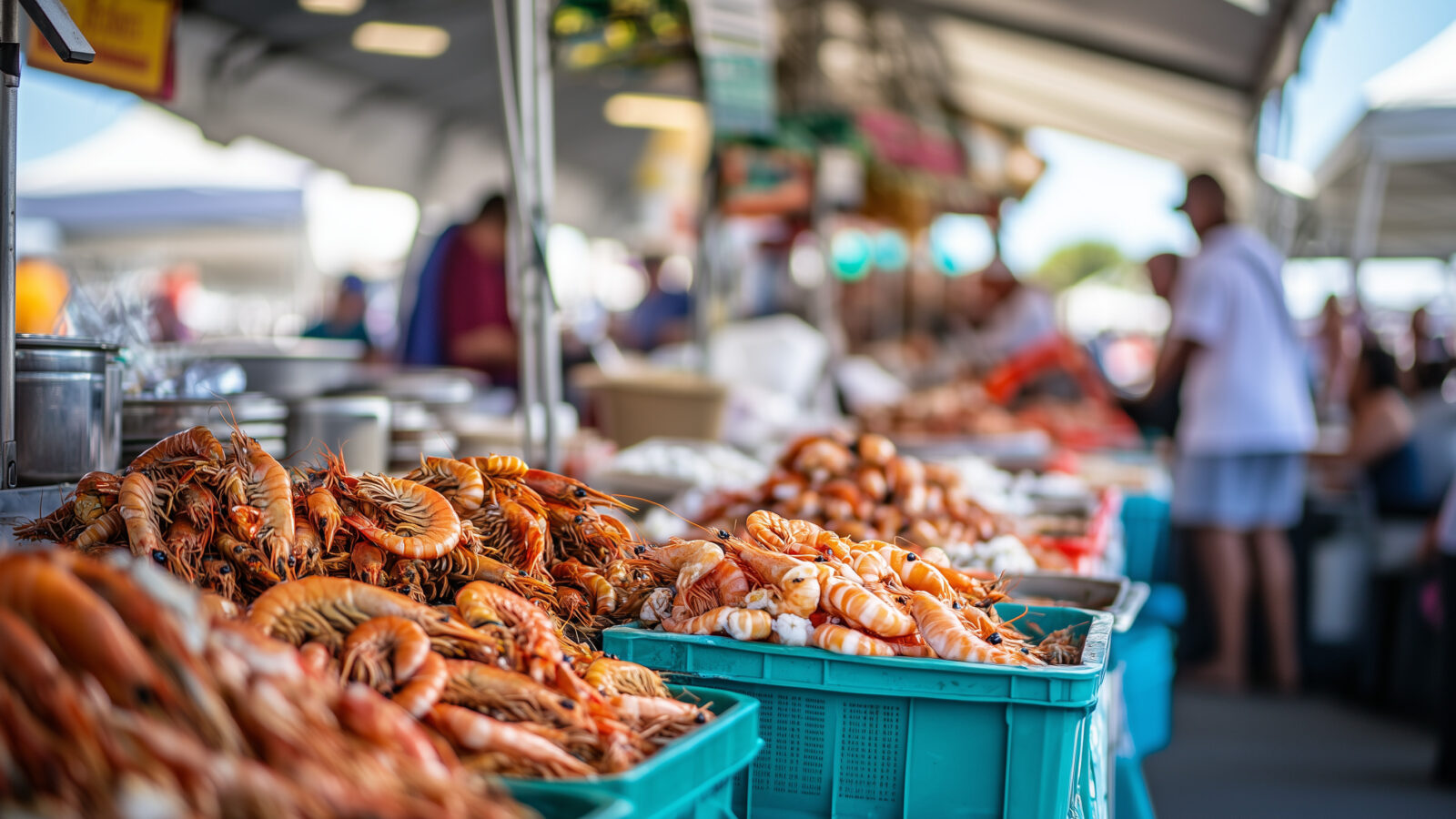 boxes of shrimp in the foreground photographed at low depth of field so the market in the background is out of focus