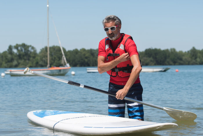 man next to a stand-up paddle board on water