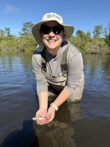 kate rose standing in the water, holding a small fish