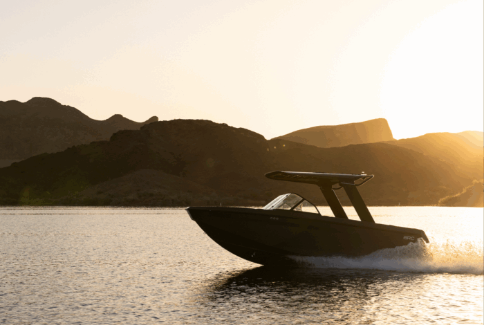 a boat on the water with mountains in the background and the sun at a low angle
