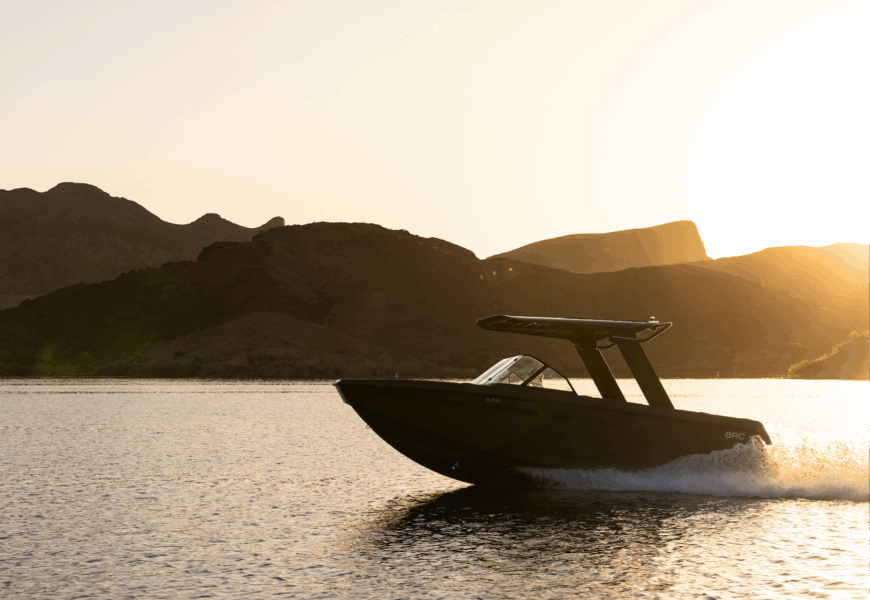 a boat on the water with mountains in the background and the sun at a low angle