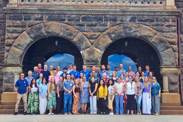 a large group of people posing in front of two large stone archways