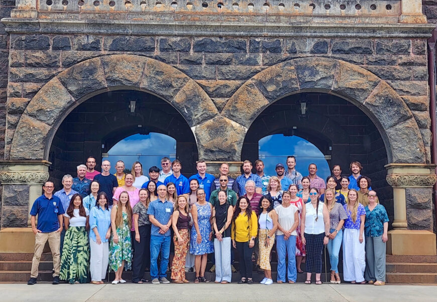 a large group of people posing in front of two large stone archways