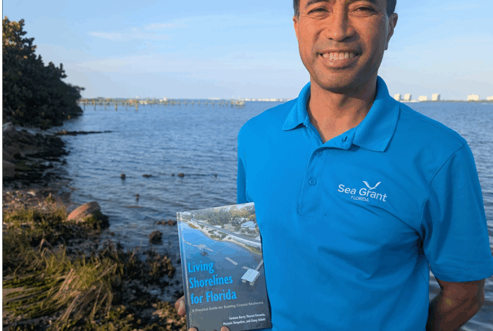Vincent Encomio holding the book living shorelines for Florida