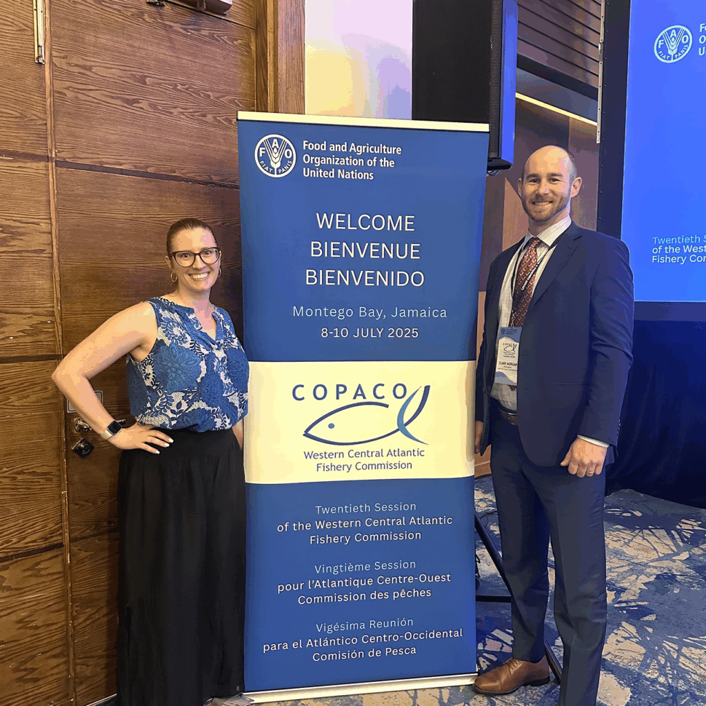 Hayley Lemoine and Clark Morgan standing next to a welcome banner