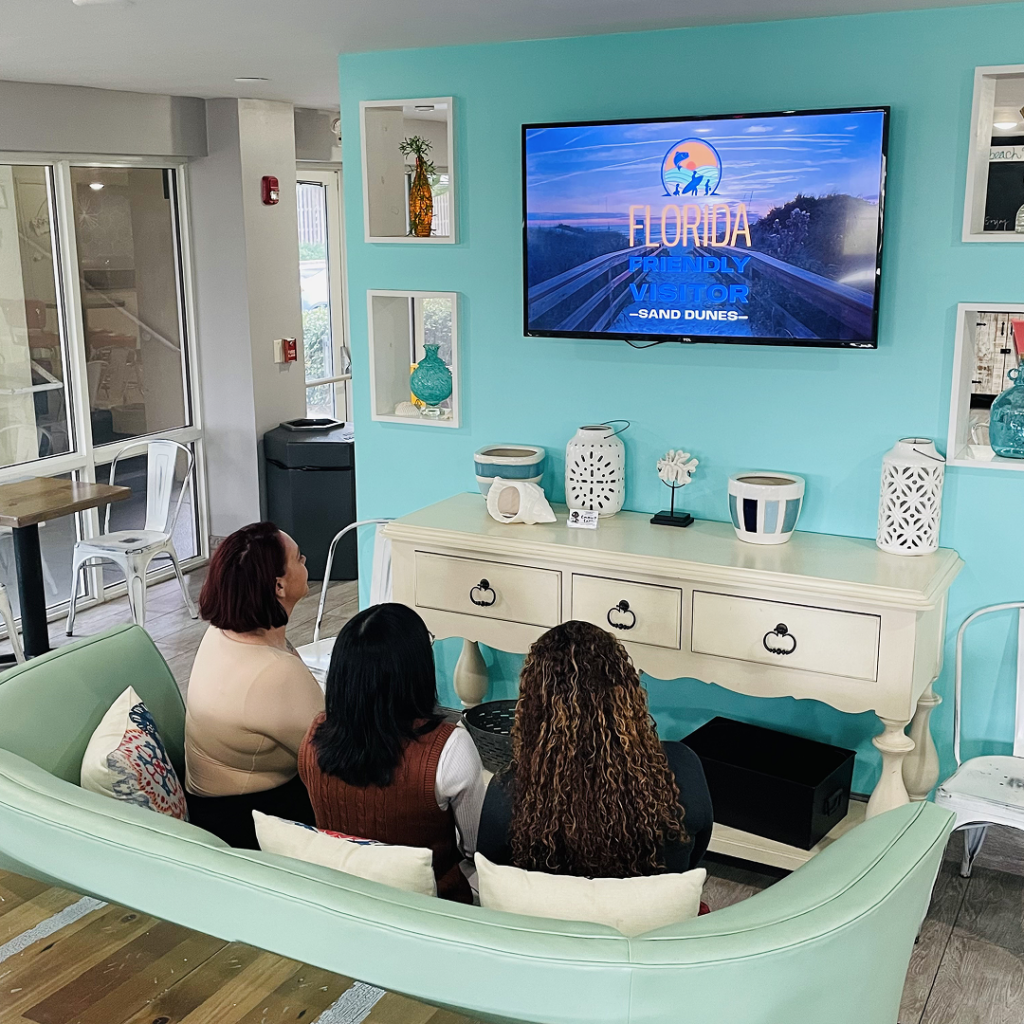 three people sitting on a couch watching tv