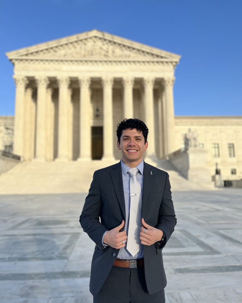 Roberto stands outside the Supreme Court Building in Washington, D.C., facing away from the building.