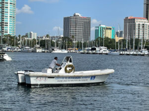 Pumpout boat on the water with operator driving it and marina in background