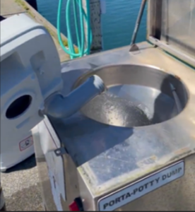 a portable toilet waste tank about to pour waste into a dump station on a dock