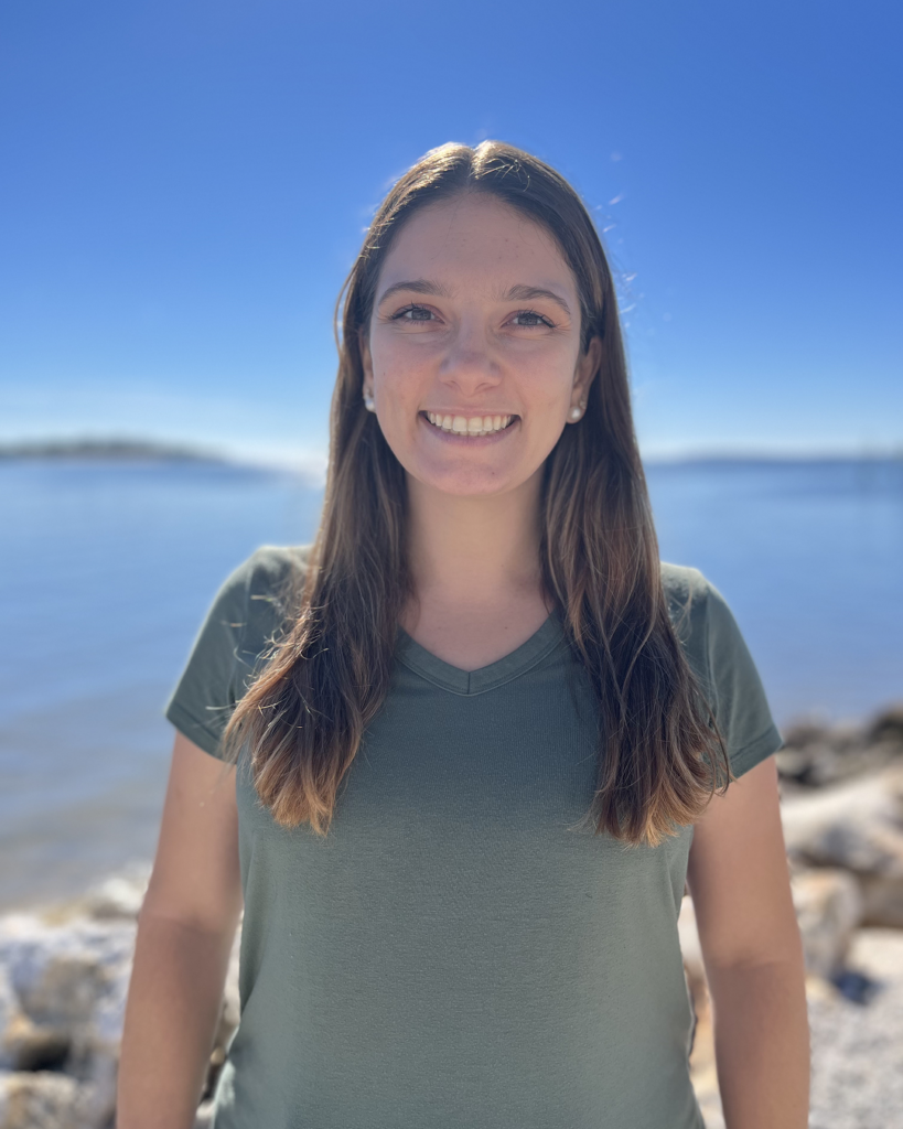 Finella Campanino smiling in front of a rocky shoreline.