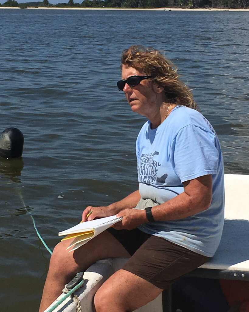 Leslie Sturmer sitting on the edge of a boat with a clipboard