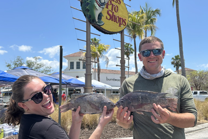 two people holding up fish in front of a bass pro shops