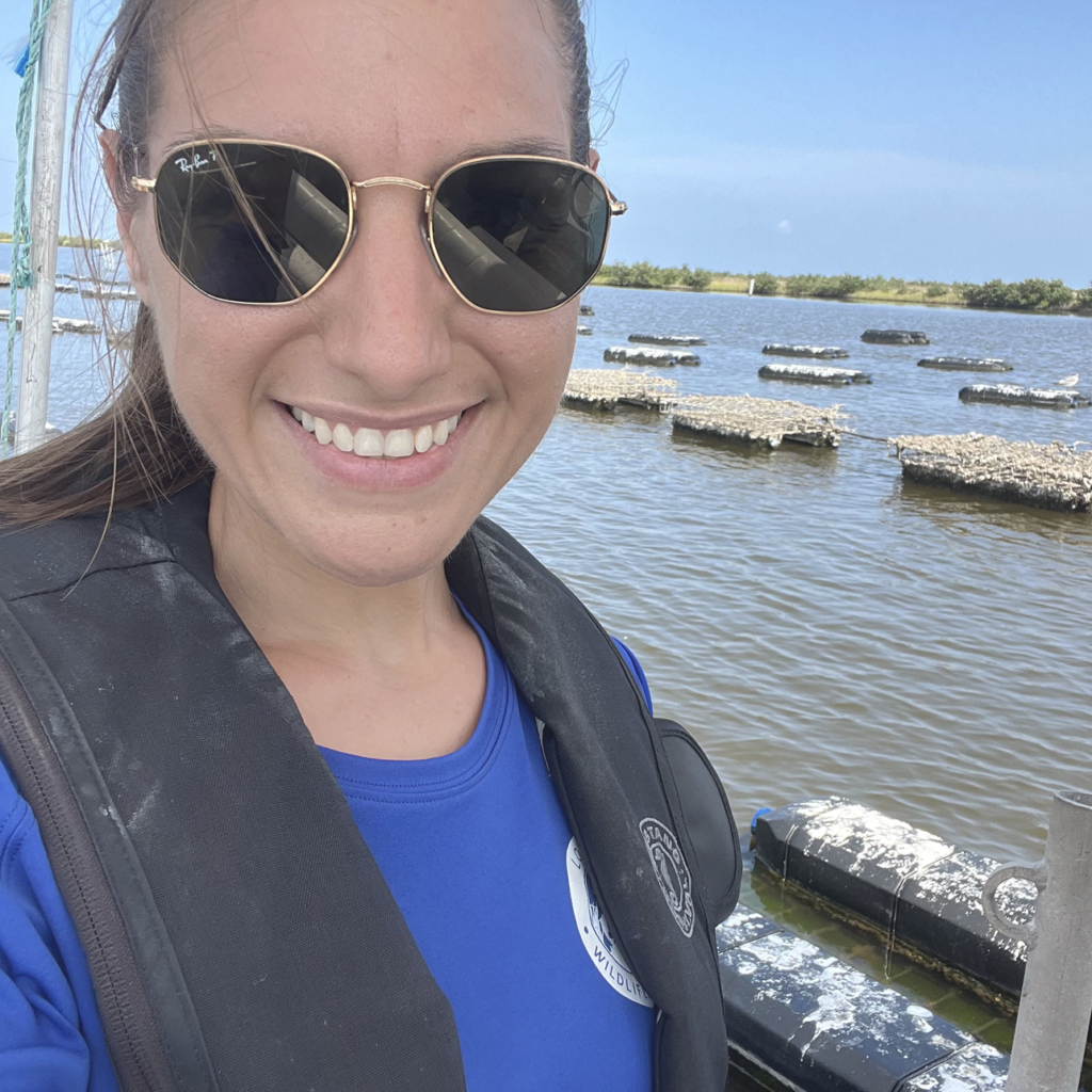 Dr. Sharon Cilano smiling in front of floating oyster cages above water.